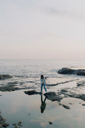 files/person-stands-on-rocks-poking-out-of-the-ocean-shoreline.jpg